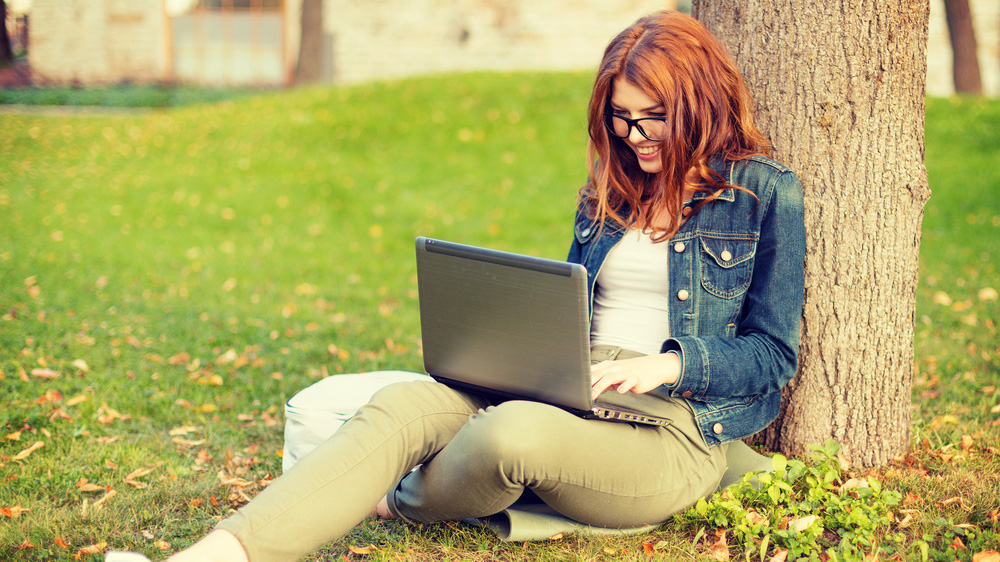 An online student works on her computer outside.