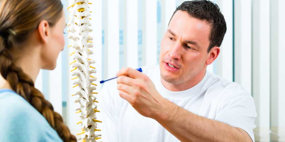 A chiropractor uses a skelton to show spinal movement.