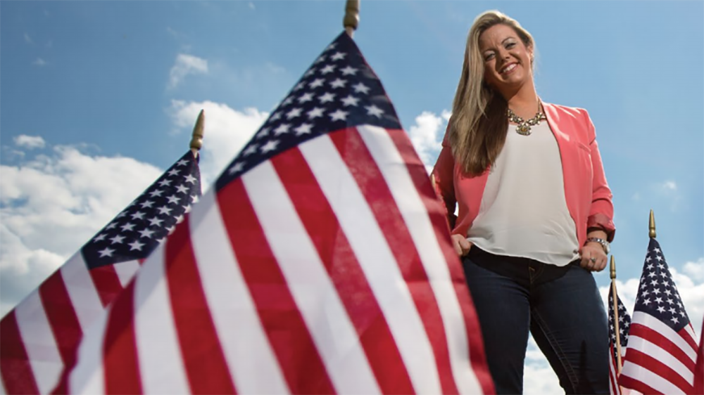 A PennWest California student poses with American flags.