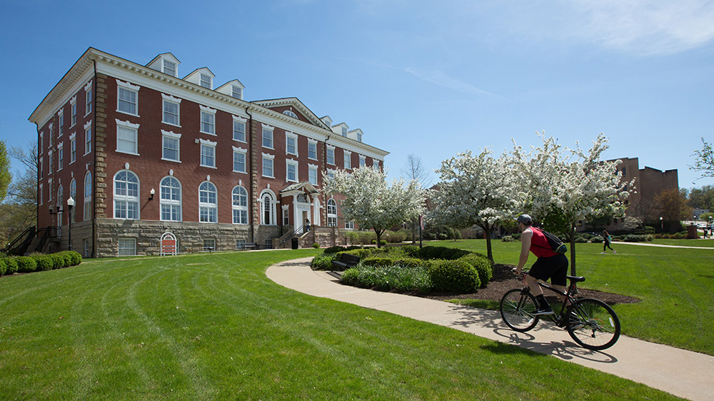 A PennWest California student riding his bike on a beautful day at campus.