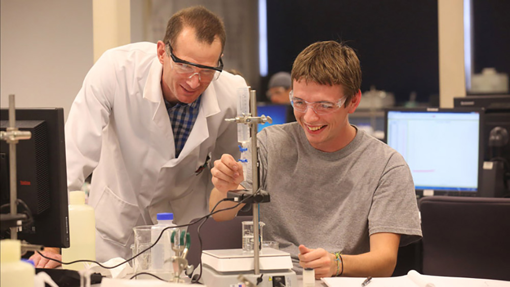 A professor helps with a chemistry experiment.