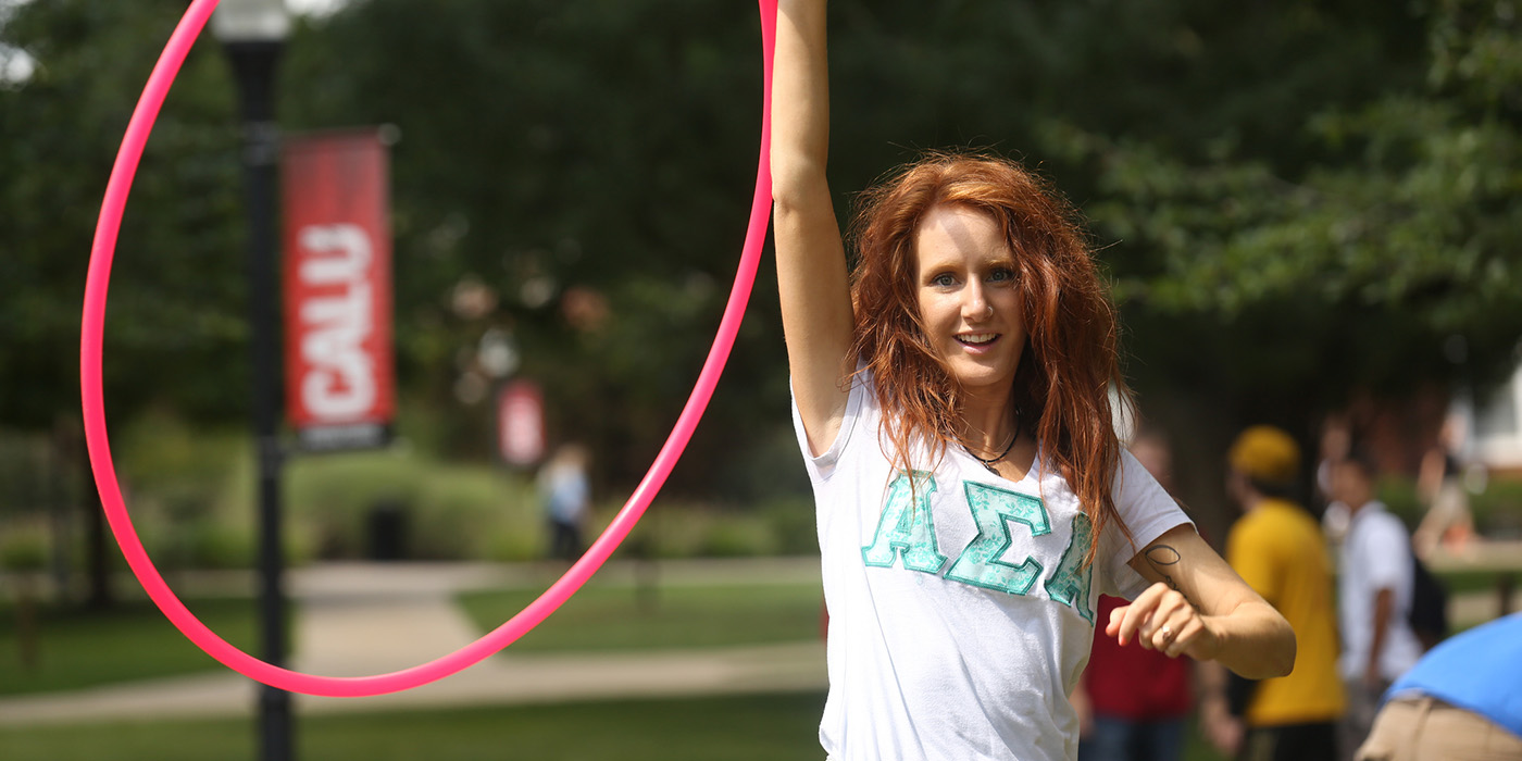 A student wearing Greek letters twirls a hula-hoop.